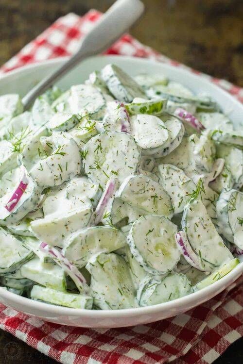 Fresh creamy cucumber dill salad with visible cucumber slices and dill in a glass bowl